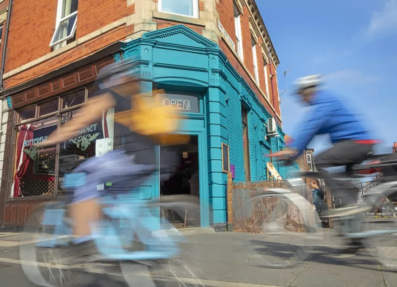cyclists speed past a cafe