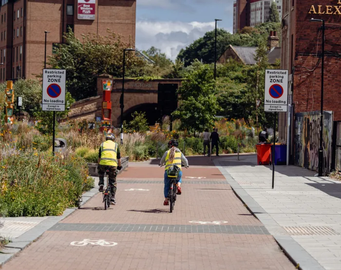  a couple of people riding bikes down a sidewalk